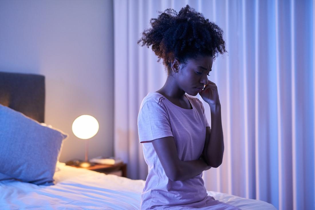woman sitting on end of bed unable to sleep because of insomnia