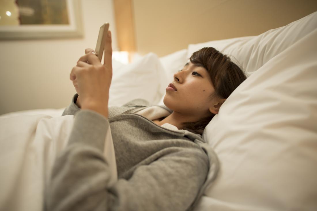 Woman looking at smartphone in bed
