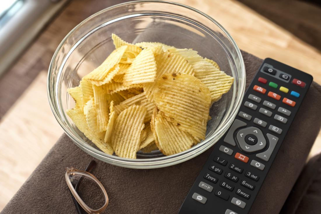 Chips or crisps in bowl next to tv remote