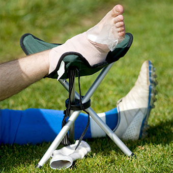 A soccer player rests and elevates his injured foot with a compression bandage and an ice pack.