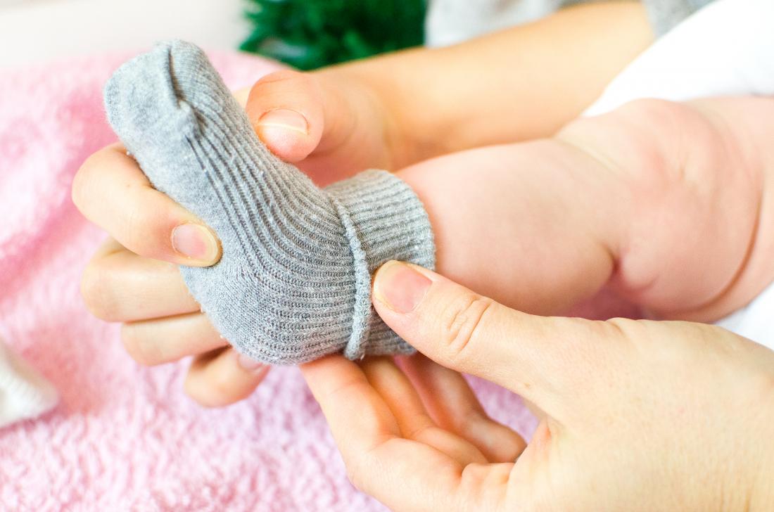 Person putting socks on the feet of a baby or infant child.