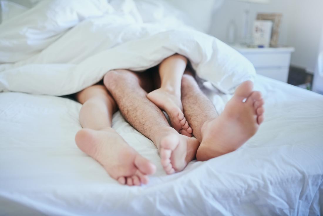 Couple in bed with feet sticking out of the duvet