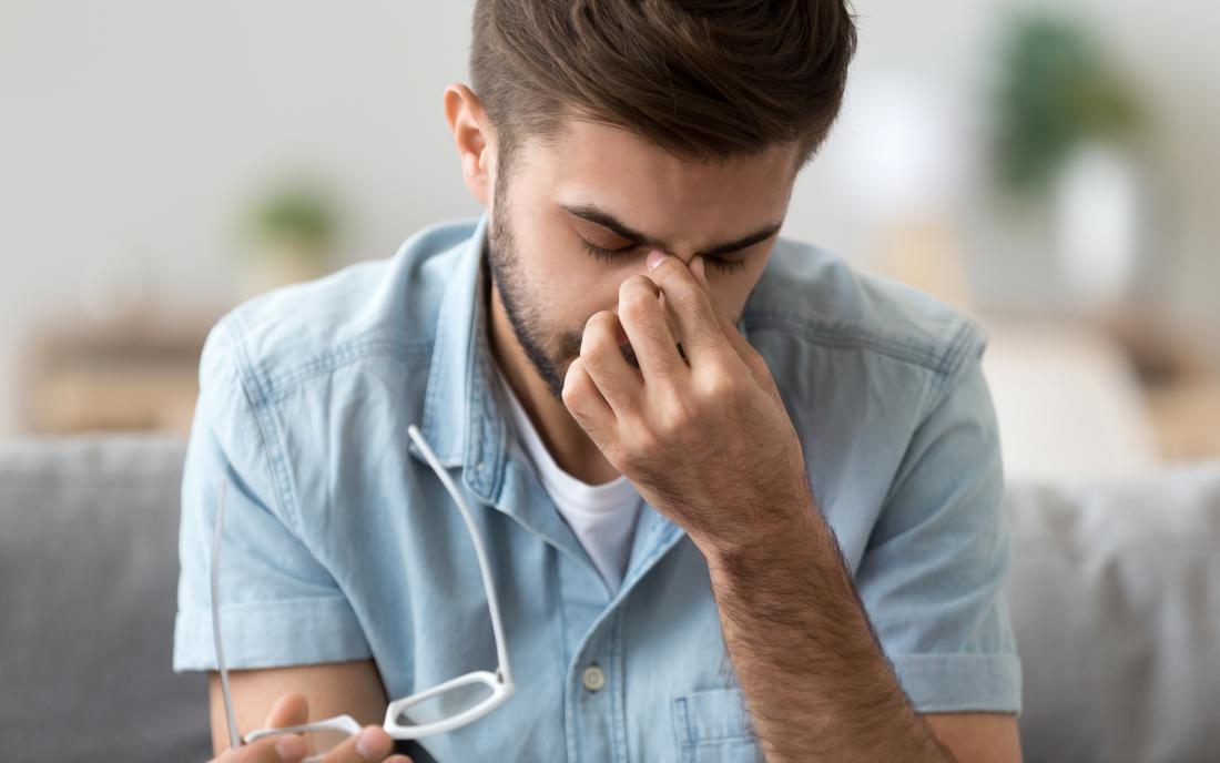 man with headache or eye strain holding bridge of nose because of sinus pain