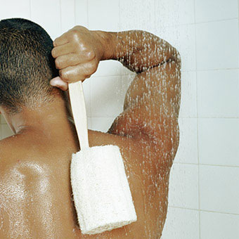 A man uses a loofah brush while taking a shower.