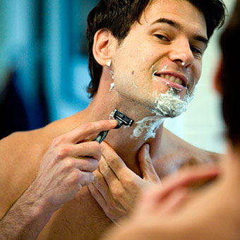 A man shaves his face and neck.