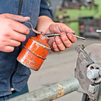 A machinist applies cutting oil to a tool.