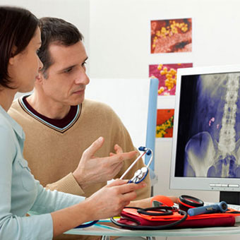 A doctor discusses causes of a patient’s kidney stone by viewing his X-ray.
