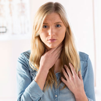A woman with laryngitis holds her sore throat.