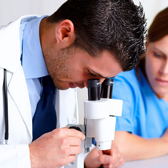 A doctor looks through a microscope for mites found from a skin scraping test for scabies.