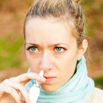 A woman using nasal spray.