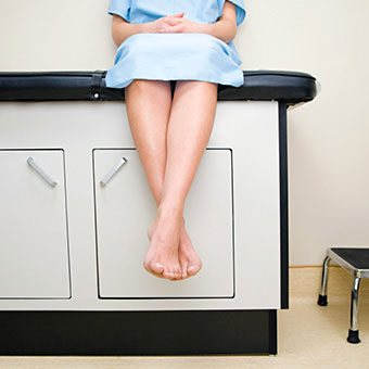 Alt TextA woman waits in a doctor's medical exam room.