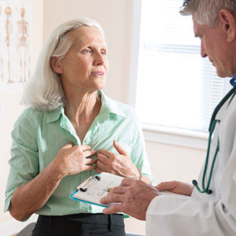 A woman explaining symptoms of shortness of breath and chest pain to her doctor.