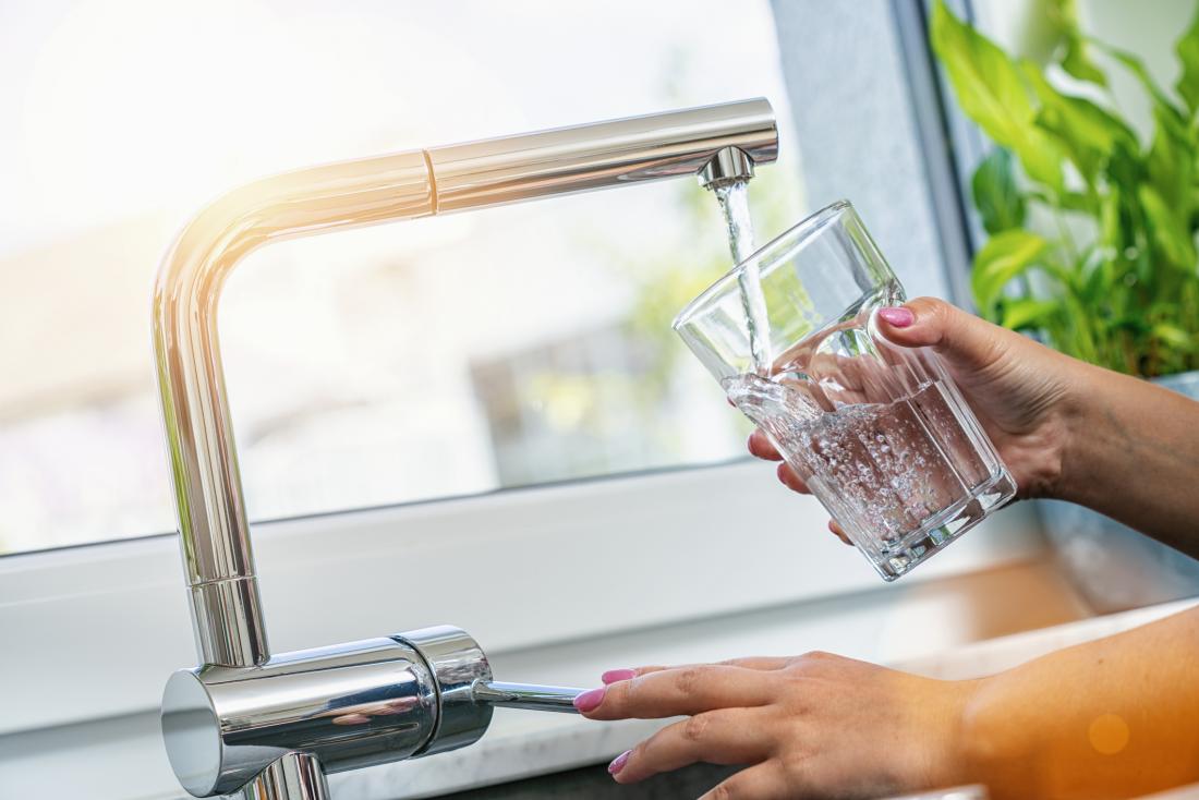 close up of woman's hands pouring tap water