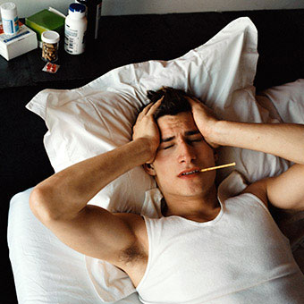 A man in bed with a fever sweating.