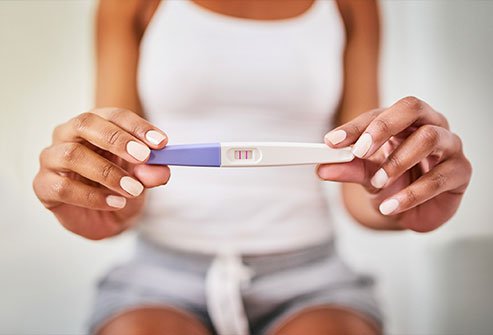 Image showing a woman holding a home pregnancy test showing results.