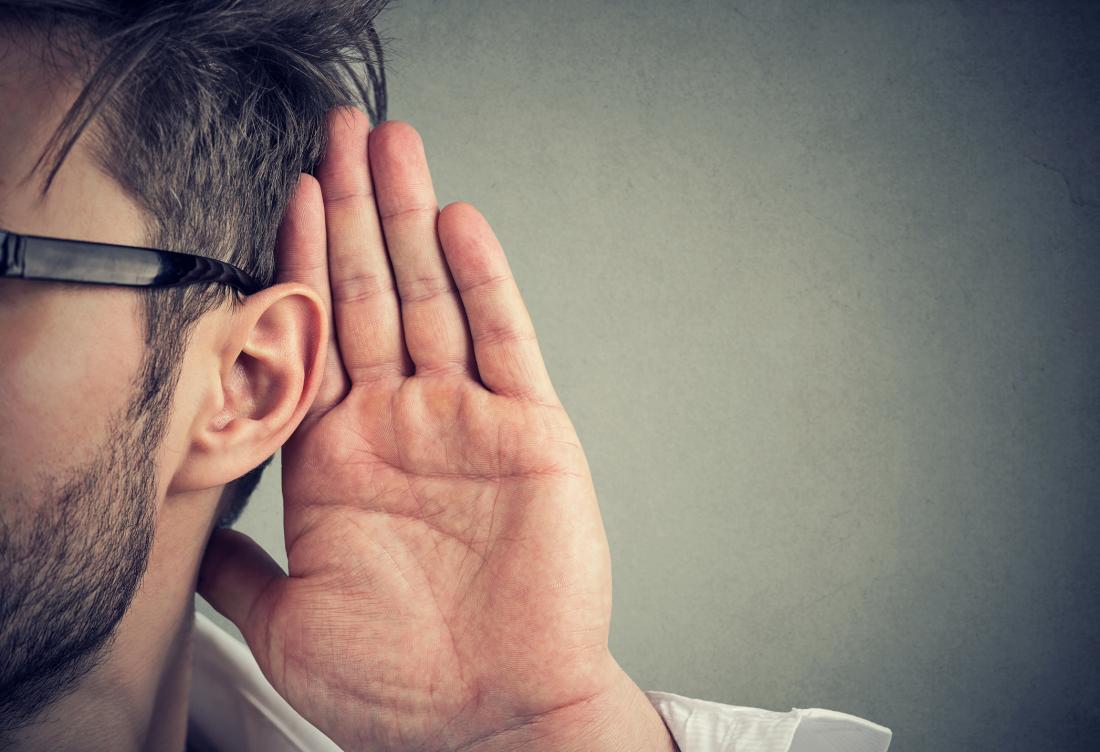 man placing hand next to ear to hear better
