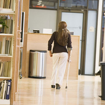 A woman with multiple sclerosis walks down a hallway.