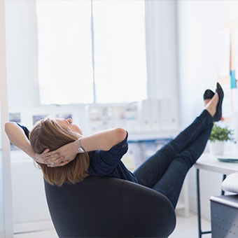 A woman relaxes with her feet up on her desk.