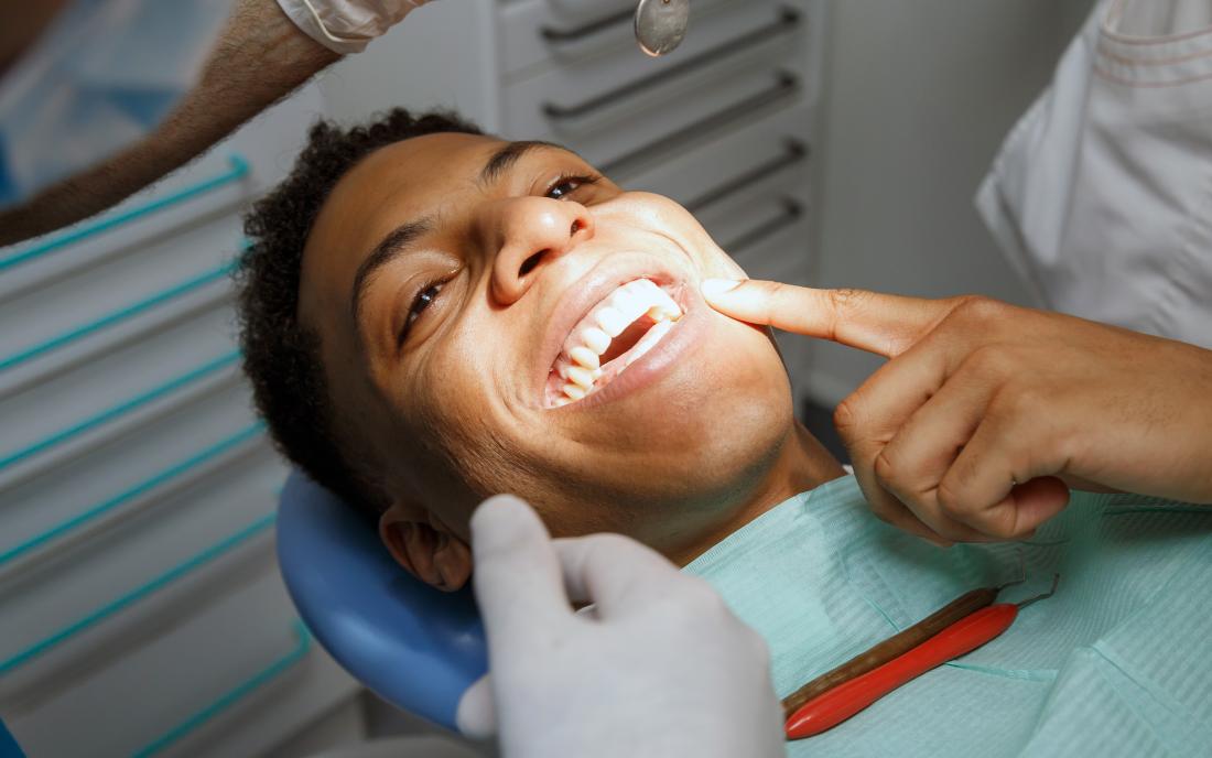 a man lying down on a dentists chair as he gets a Fluoride treatment