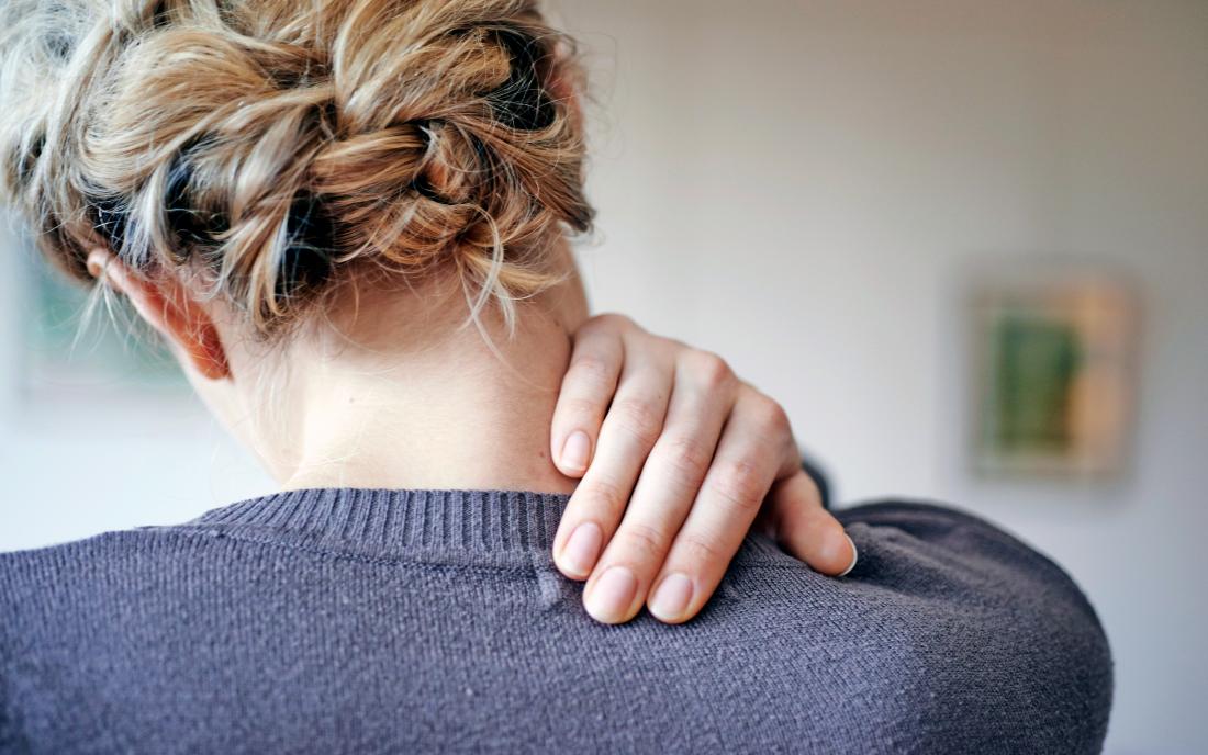 a woman holding her shoulder because she has thoracic outlet syndrome