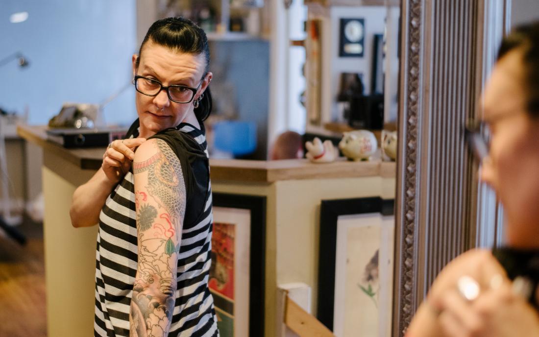 a woman looking at her tattoo because it's itchy. 