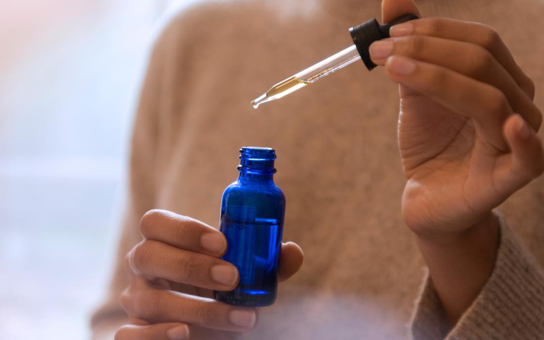 a woman holding a bottle of essential oils that she is using to treat high blood pressure 
