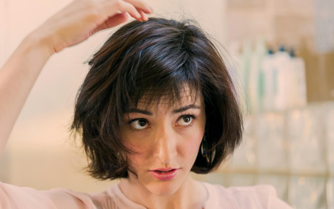 a woman checking her head for hair loss from seborrheic dermatitis
