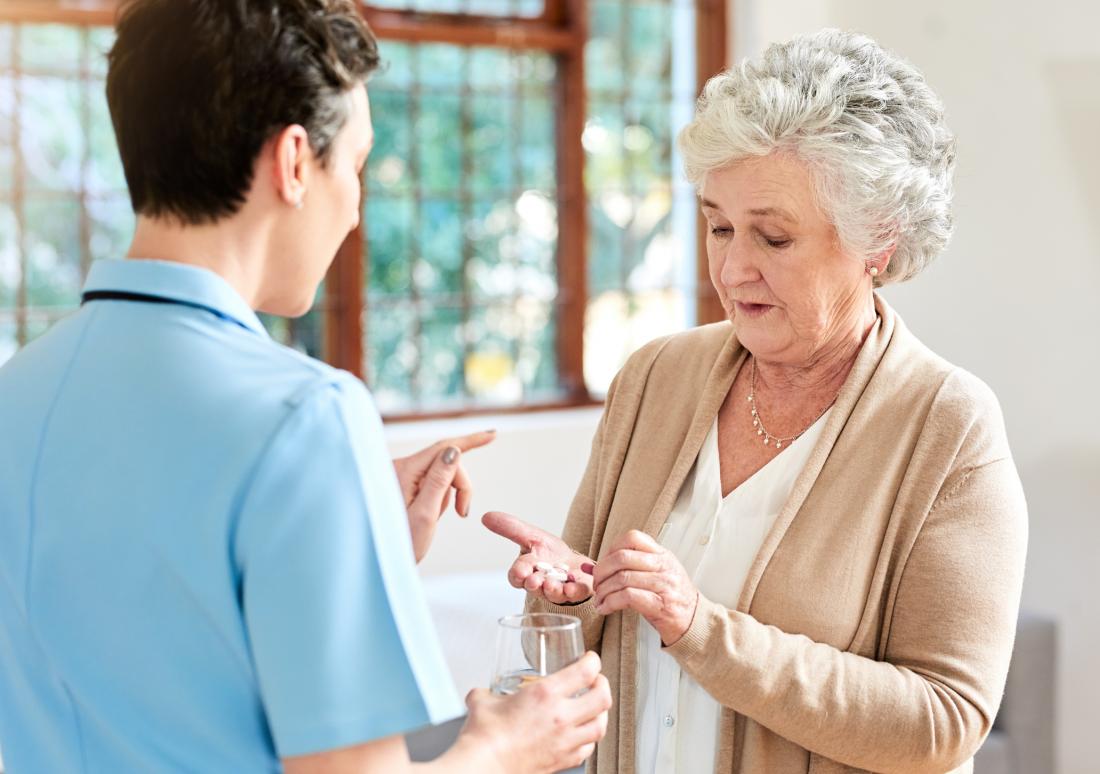 nurse giving drugs to senior lady