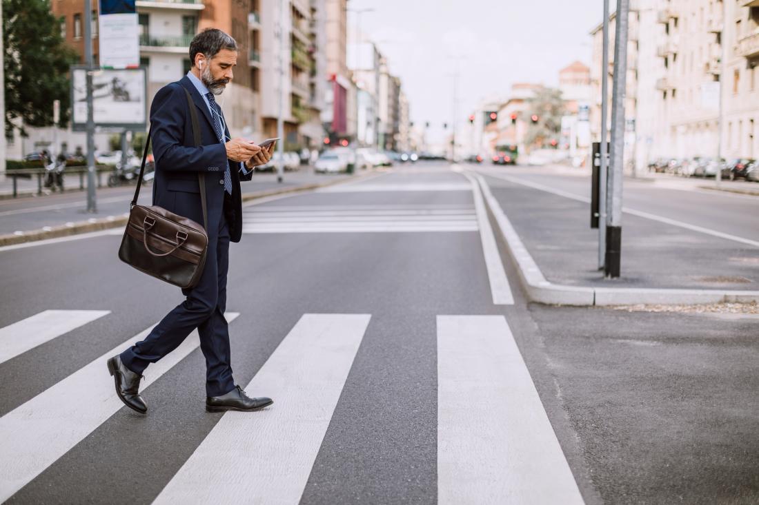man crossing zebra while texting