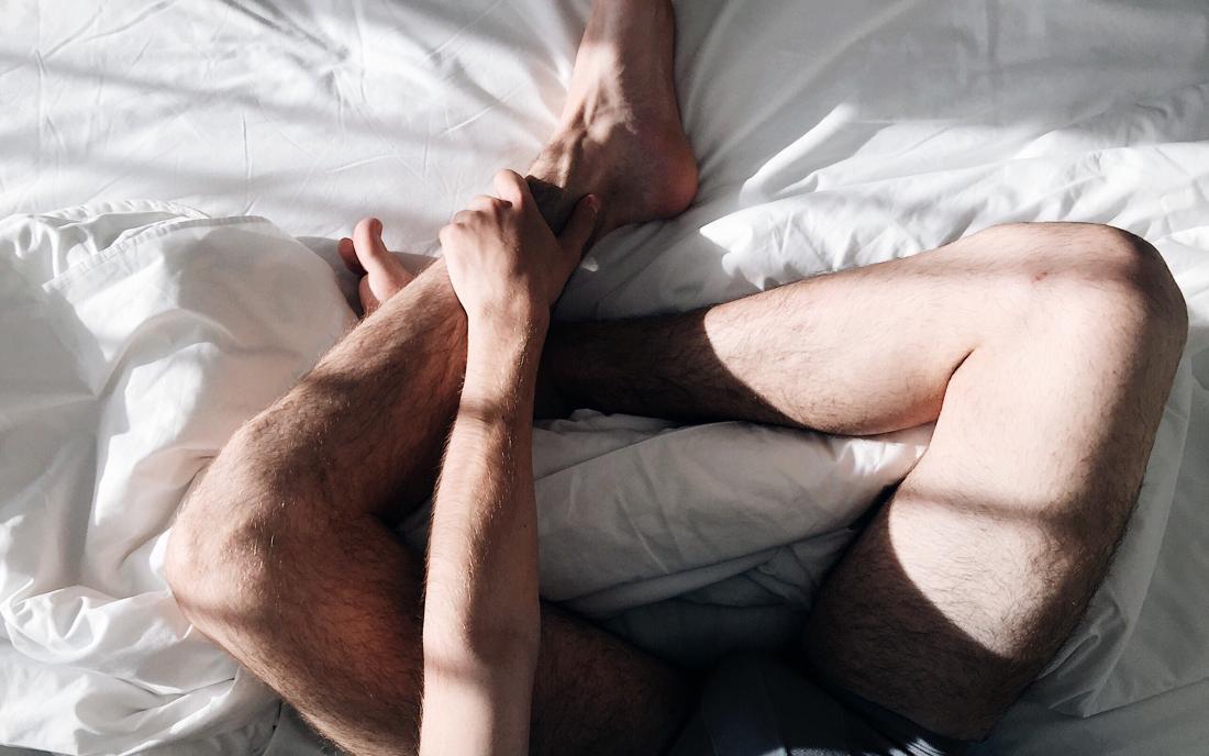 A Males legs in bed who is wondering if his discharge is normal