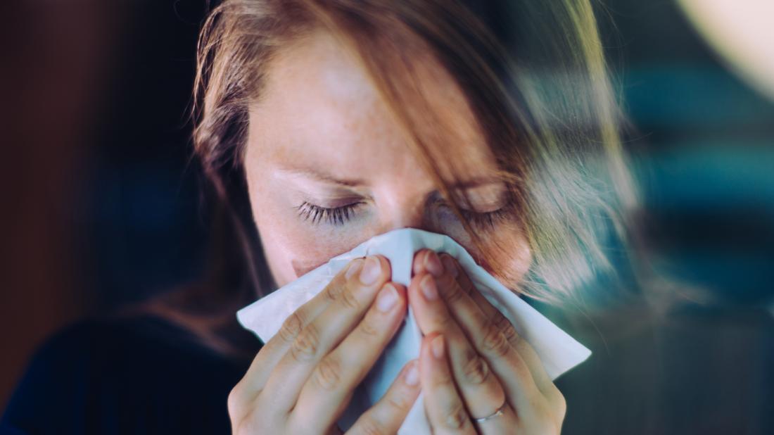 a woman experiencing a runny nose because of the early stages of a cold 