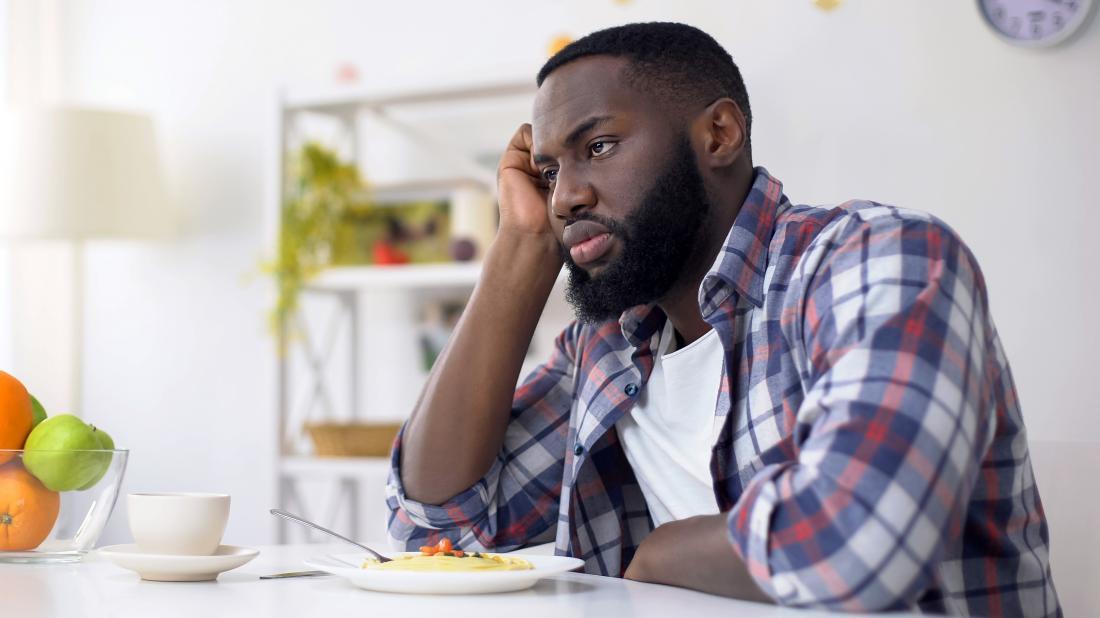 a man not eating a bowl of food in front of him because he has a loss of appetite due to anxiety 