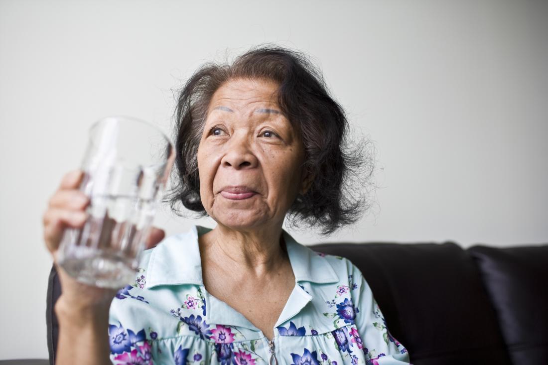 senior woman holding glass of water