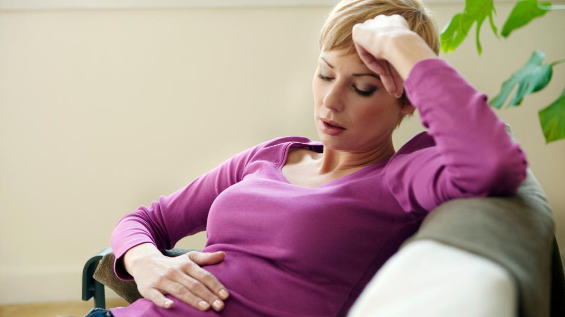 a woman holding her stomach because she is experiencing Lower abdominal pain and bloating