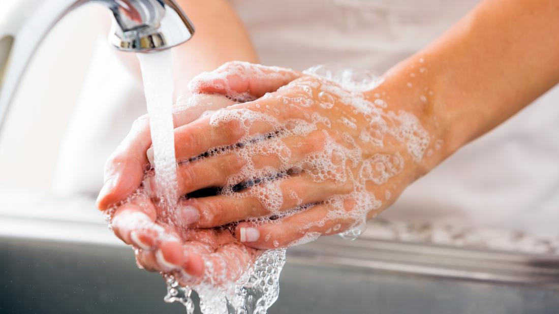 a woman washing her hands with soap because she has bleach on her skin