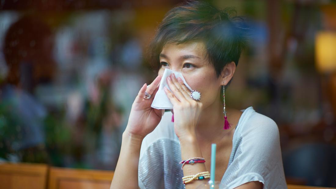 a woman blowing her nose because she has ethmoid sinusitis